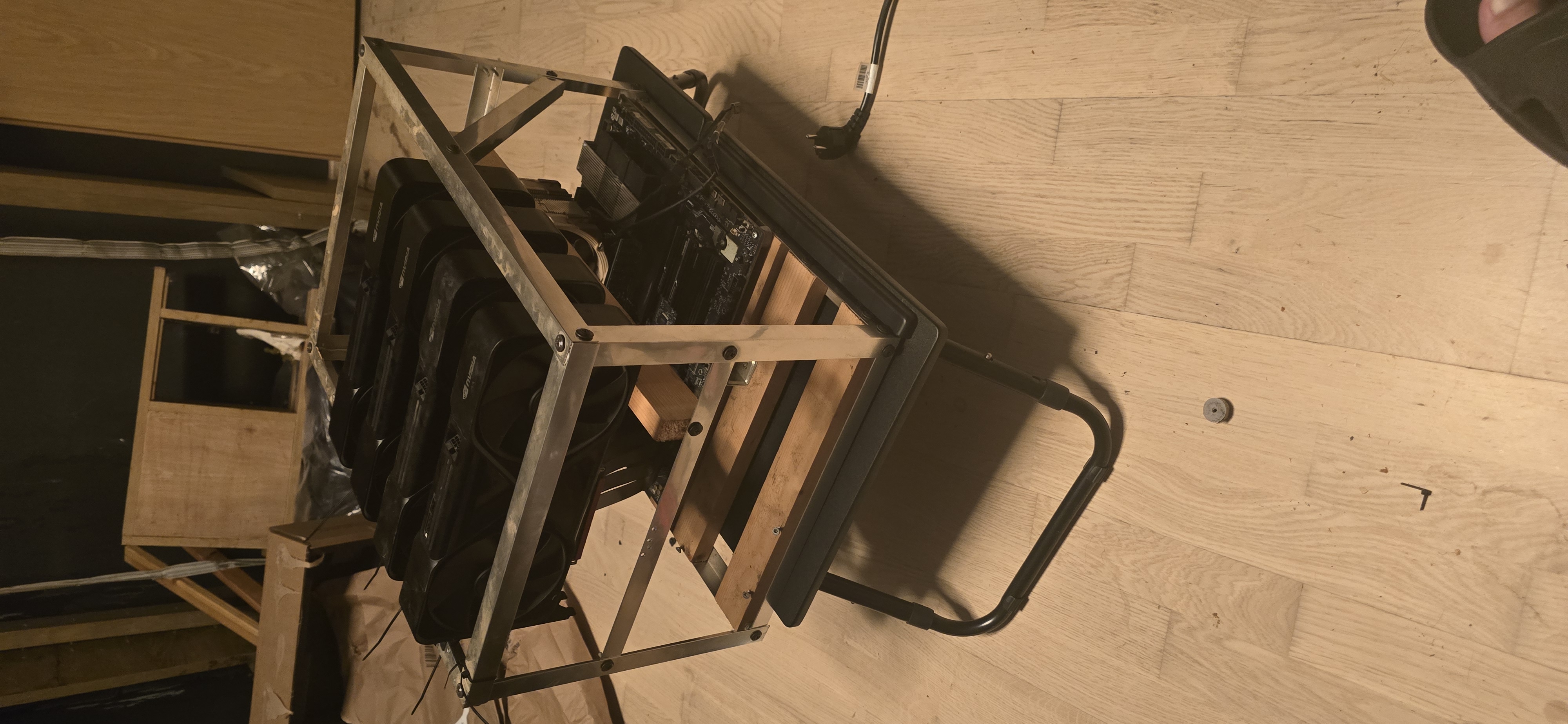 The aluminium-frame chassis with four NVIDIA Blackwell cards mounted in a row, Noctua-cooled, on a stand in a dark workshop.