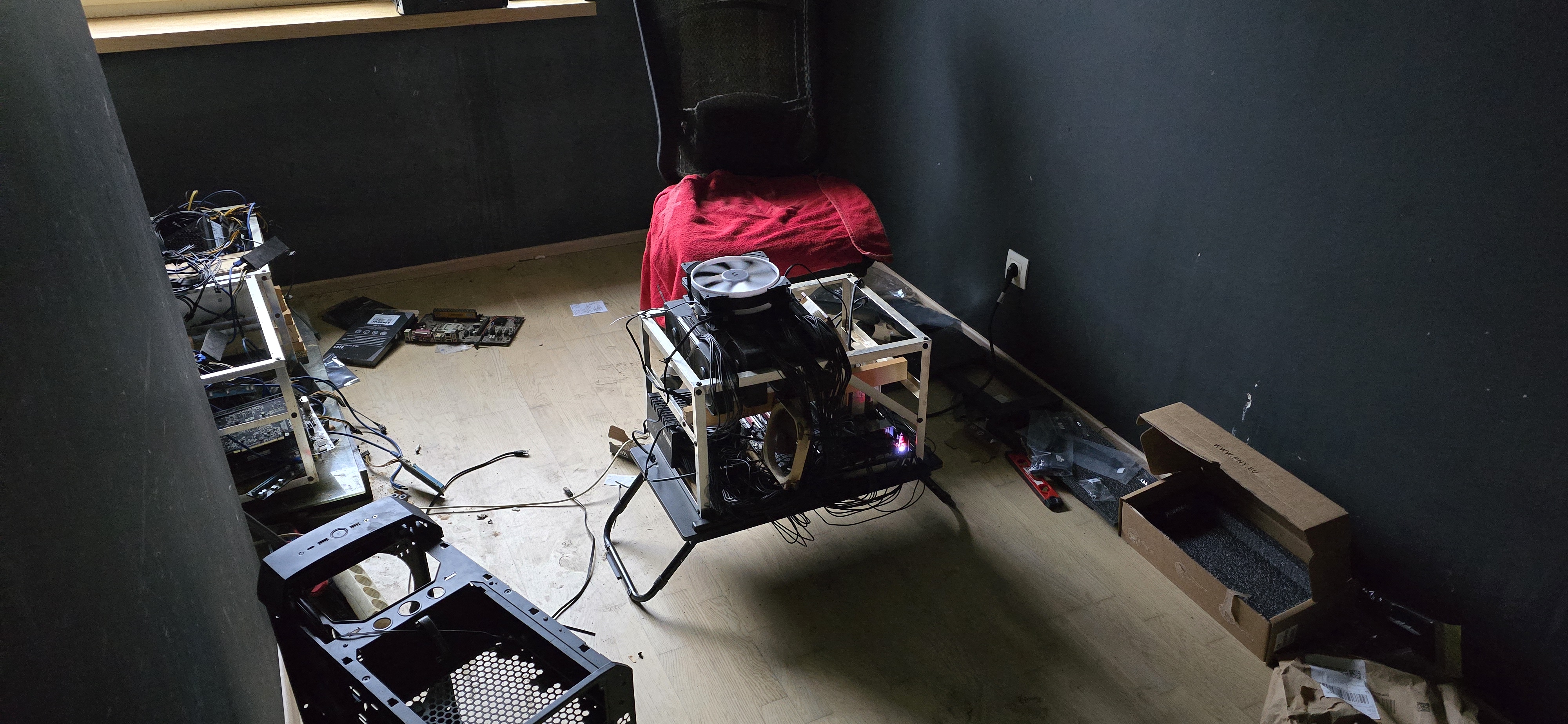 The rig mid-build: a wooden-frame chassis with a Noctua fan on top, cables everywhere, on a stand in a dark workshop.
